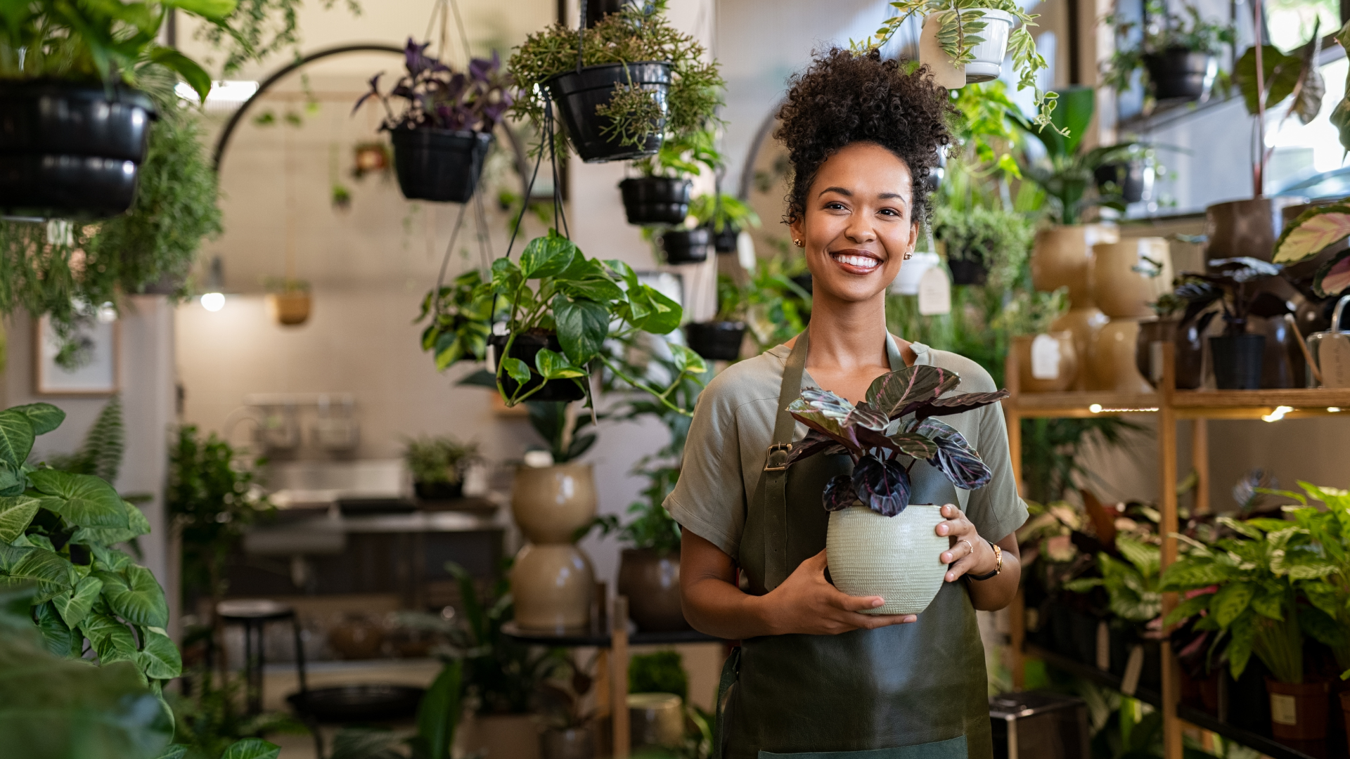small florist business and woman business owner is holding plants in here shop
