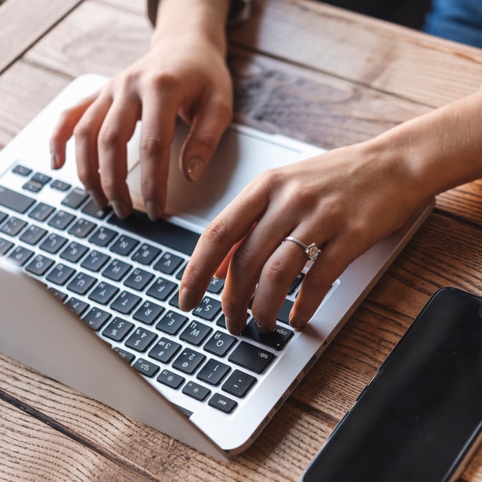 close-up-woman-typing-laptop-coffee-shop