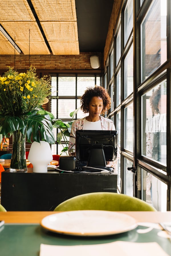 female-manager-standing-her-restaurant-using-computer