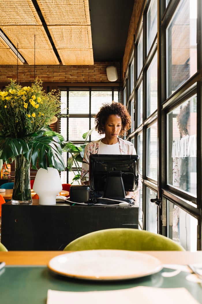 female-manager-standing-her-restaurant-using-computer